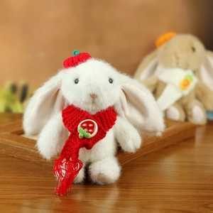 Close-up of white plush bunny keychain with red knit strawberry hat and scarf details