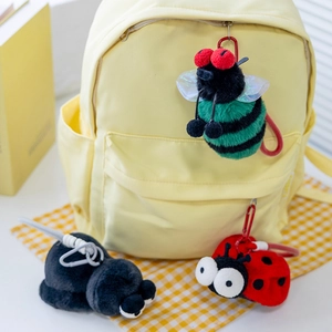 Dettagli dei ciondoli a insetto in peluche su zaino con moschettoni e corde colorate vivaci