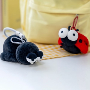 Dettaglio di portachiavi in peluche a forma di ragno e coccinella su uno zaino giallo