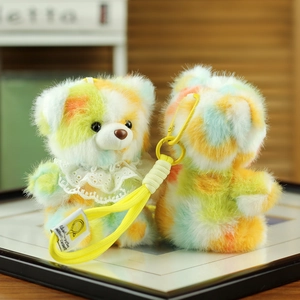 Detailed close-up of a colorful plush bear charm with lace collar and yellow lanyard