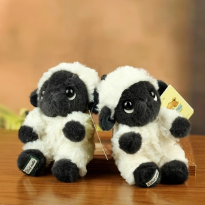 Detailed view of two plush lamb toys on a wooden surface with brand foot labels