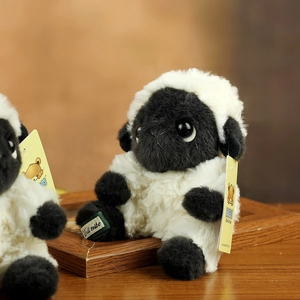 Detail of a white lamb plush toy with curly fur, featuring brand tags and rustic wooden decor