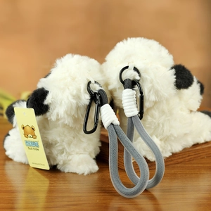 Close-up of fluffy white dog plush keychain with black ears and braided lanyard detail