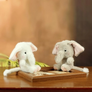 Close-up of cute plush elephant dolls in white and grey with soft pink inner ears