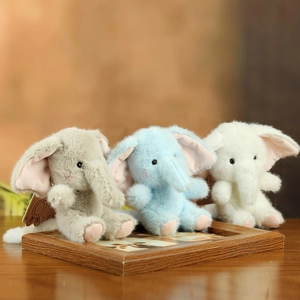Detailed view of three soft plush elephant keychains in grey, blue, and white colors