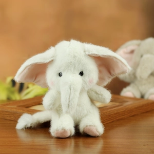 Close-up of cute plush elephant keychain with soft fur, pink ears and warm background