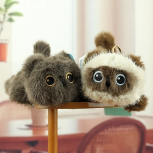 Plush cat keychains in grey and Siamese brown colors on a wooden shelf in a cozy setting