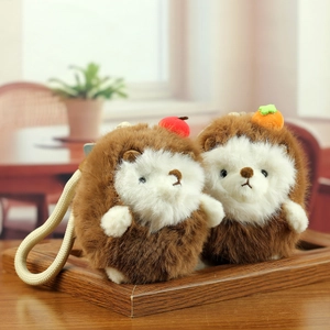 Cute plush hedgehog keychains with apple and persimmon decorations on a wooden tray