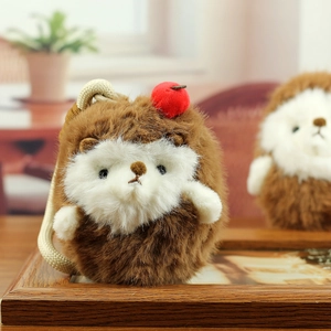 Close-up of cute plush hedgehog keychain with soft fur and a red apple on the head
