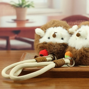 Close-up of hedgehog plush charms with woven rope on a dark wooden tray