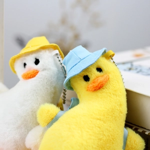 Close-up of cute plush duck keychains in white and yellow with colorful sun hats