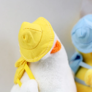 Close-up of white plush duck pendant with tiny yellow straw hat and mini backpack detail