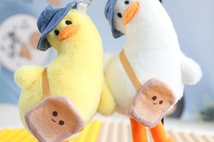 Close-up of cute plush ducks with denim hats and toast bags for bags and keys