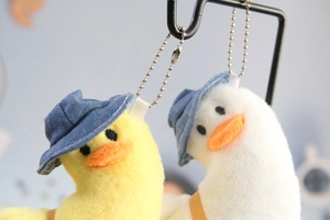 Close-up of yellow and white plush duck keychains with blue hats and silver chains