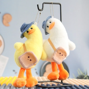 Close-up of plush duck keychains with blue sun hats and toast-shaped bags on silver chains