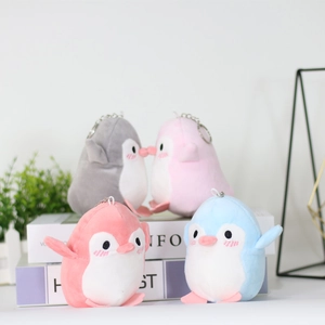 Close-up of colorful plush penguin keychains with metal rings on decorative books