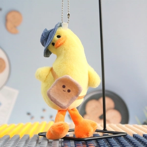 Close-up of yellow plush duck keychain with denim hat and toast bag on a display stand