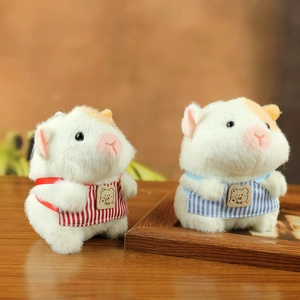 Cute plush guinea pig pendants with striped aprons and bear patches on a wooden table