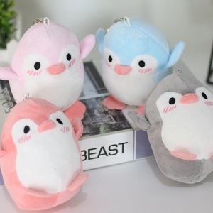Close-up of cute plush penguin keychains in pink, blue, and grey with metal rings