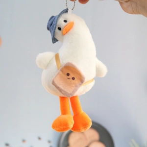 Detail of cute plush duck keychain wearing blue hat and smiling toast crossbody bag