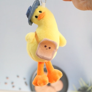 Detail of yellow plush duck keychain wearing a blue denim hat and toast bag accessory