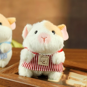 Macro detail of cute white plush guinea pig keychain with red striped apron on wood