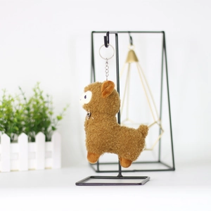 Detail of cute brown alpaca plush keychain with silver metal ring on a display stand