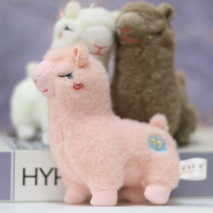 Close-up of pink alpaca plush keychain with soft fur detail and embroidered golden symbol