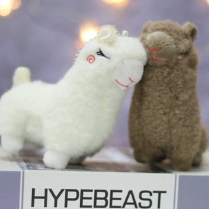 Detail of white and brown alpaca plush keychains with soft faux wool and bead chains