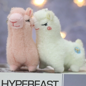 Close-up of fluffy pink and white alpaca plush keychains with metallic chain and embroidery