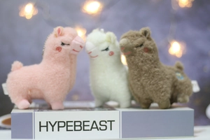 Three plush alpaca keychains in pink, white, and brown with soft curly fur and metal chains