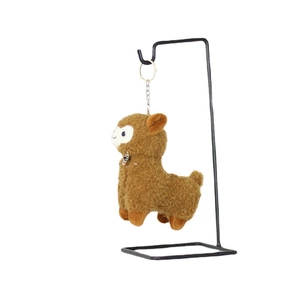 Brown plush alpaca keychain with plaid bow tie hanging on a metal display stand