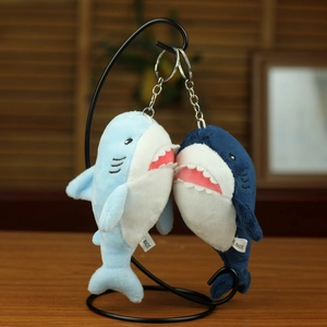 Cute plush shark keychains in light and dark blue hanging on a metal stand for bag decor