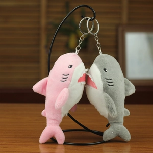 Detail of gray and pink plush shark charms with metallic keychains and soft embroidery