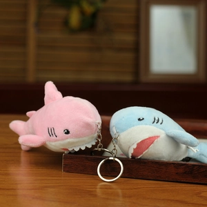 Close-up of cute pink and blue plush shark charms with metal keychains on a tray