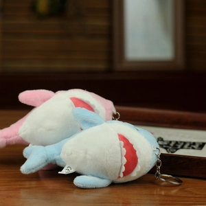 Detail of pink and blue plush shark charms with metal keychains and safety labels