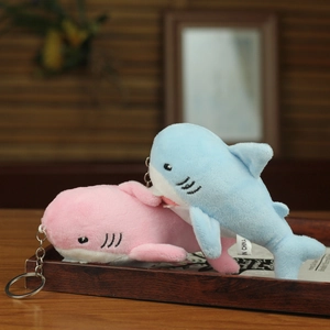 Detail of cute blue and pink plush shark keychains on a wooden tray with metal rings