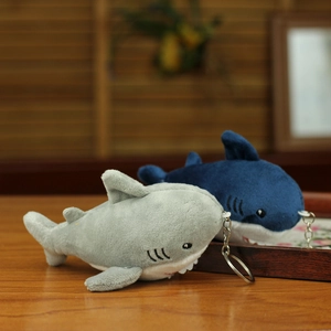 Close-up of grey and blue plush shark pendants with metal keychains on a wooden table