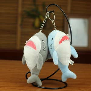Close-up of plush shark pendants in blue and grey with silver keychains on a stand