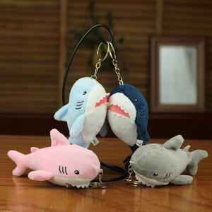 Plush shark keychains in four colors hanging on a metal rack for backpack decoration