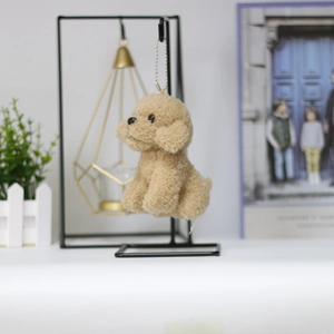 Close-up of a curly plush teddy dog keychain with silver chain hanging on a metal rack