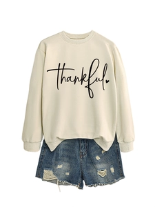 Flat lay of apricot sweatshirt with thankful print and distressed denim shorts