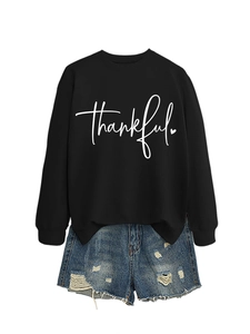 Detail view of black long sleeve sweatshirt with thankful print and ripped denim shorts
