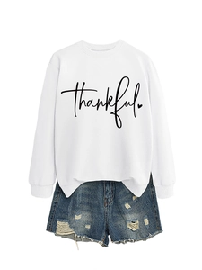 Detail of white long sleeve sweatshirt with black thankful lettering and denim shorts