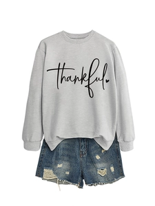 Flat lay of a light grey sweatshirt featuring thankful print and distressed denim shorts