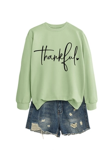 Detail of light green sweatshirt with black Thankful script and distressed denim shorts
