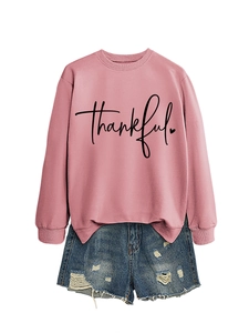Close-up of pink crewneck sweatshirt with thankful print and distressed denim shorts