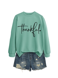 Detail of mint green sweatshirt with thankful print and distressed denim shorts