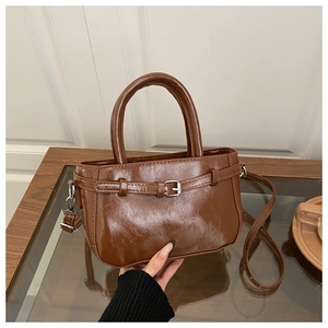 Detail of caramel brown retro handbag showing glossy texture and silver buckle hardware