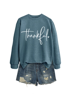 Detailed view of the 'thankful' script print on teal crewneck sweatshirt with denim shorts